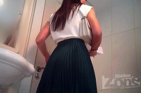 Молодая девушка в длинной юбке писает в туалете